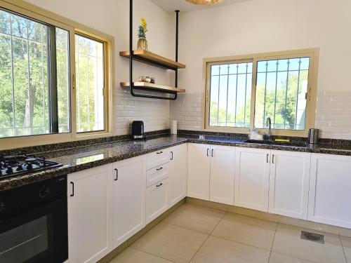 a kitchen with white cabinets and black appliances at Beit Mema in Aḑ Ḑahr