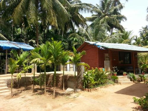 a small house with palm trees in front of it at Tendulkar Beach Resort in Diveagar