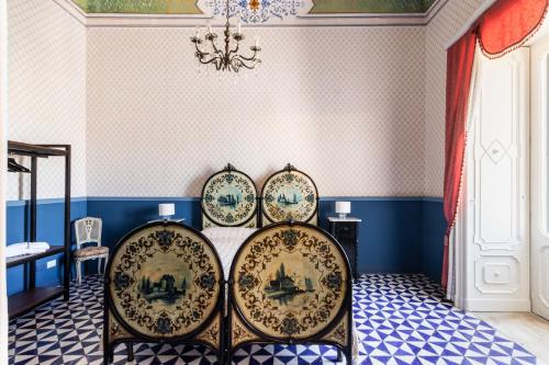 a dining room with three chairs and a chandelier at Palazzo Giangreco Luxury Rooms in Avola