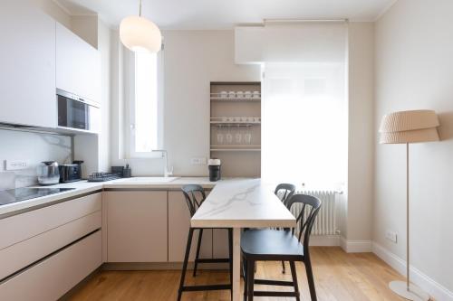 a kitchen with white cabinets and a table and chairs at Luminoso Trilocale Certosa - Mirable PM in Milan