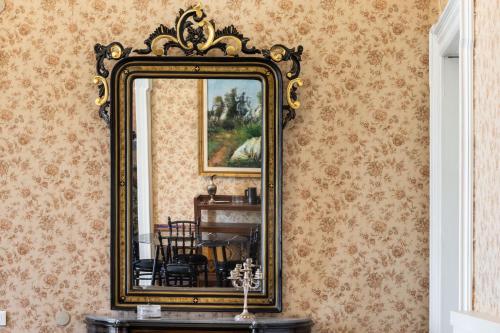 a gold mirror on a wall with a dining room at Palazzo Giangreco Luxury Rooms in Avola