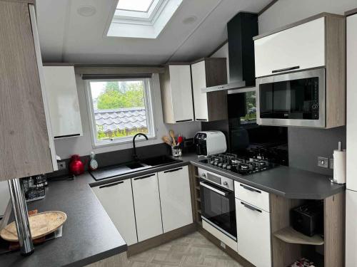 a kitchen with white cabinets and a window at Vakantiepark Klein Strand - Luxe Chalet 4p in Jabbeke