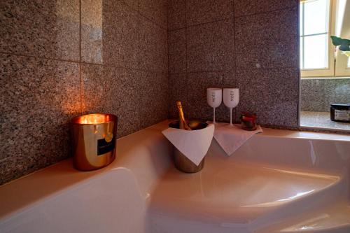 a bathroom with a tub with a candle and two wine glasses at Zlatý Lev Žatec in Žatec