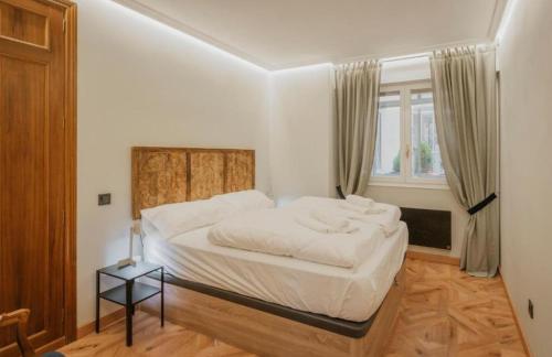 a bedroom with a bed with white sheets and a window at Centro Burgos Real Consulado 1787 in Burgos