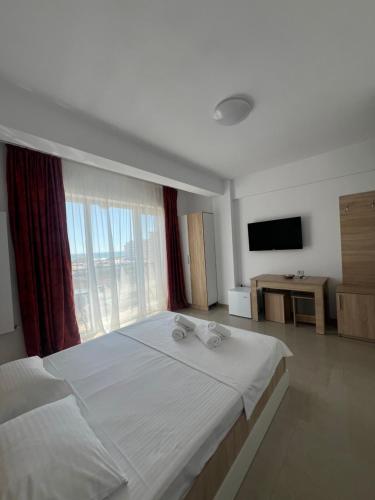 a bedroom with a large bed and a large window at Christale Rooms in Năvodari