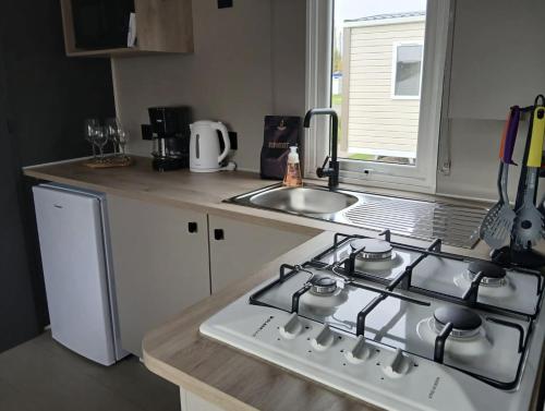 a kitchen with a stove top and a sink at Vakantiepark Klein Strand - Cottage 4p in Jabbeke