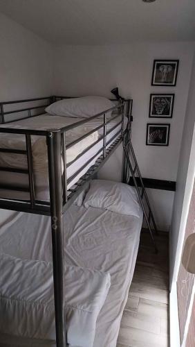 a bunk bed in a room with white sheets at Vakantiepark Klein Strand - Luxe Houten Chalet in Jabbeke