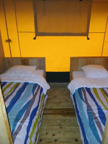 two beds sitting next to each other in a room at Vakantiepark Klein Strand - Glamping 6p in Jabbeke