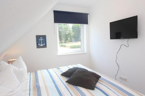 a bedroom with a bed with a television on the wall at Ferienhaus Skanhuus in Klütz