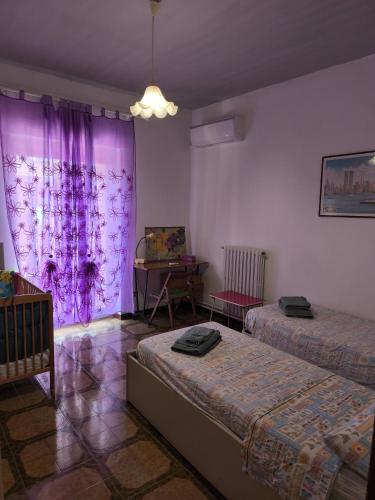 a room with two beds and a table and purple curtains at Casa Vinella in Putignano