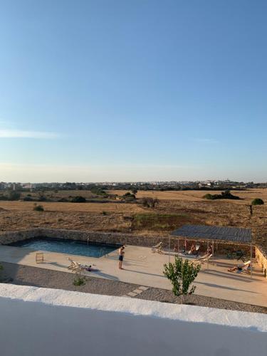 a person standing next to a swimming pool next to a field at Masseria Caposella in Ugento