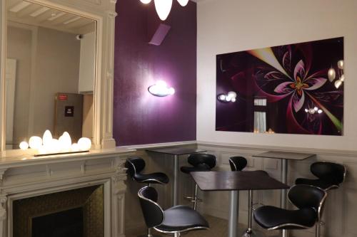 a room with a fireplace and a table and a painting at The Originals City - Hôtel Saint-Martial, Limoges Centre in Limoges