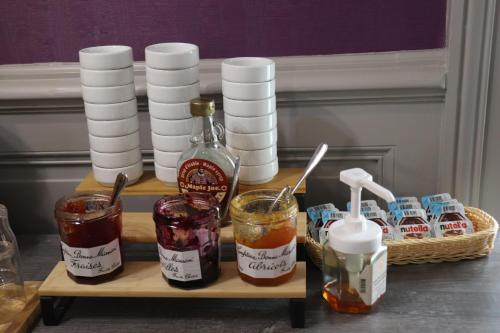 a wooden tray with jars of jam and a bottle of syrup at The Originals City - Hôtel Saint-Martial, Limoges Centre in Limoges
