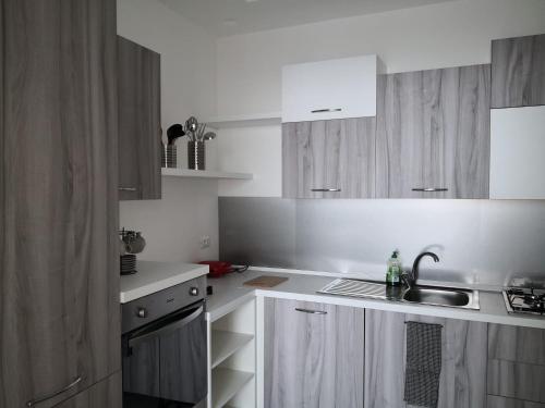 a kitchen with white cabinets and a sink in it at La casa dei Capperi - The house of capers 1 in Acireale