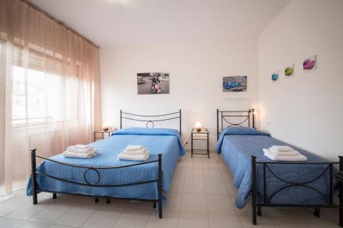 zwei blaue Betten in einem Zimmer mit Fenster in der Unterkunft Camere Oberdan in Foligno