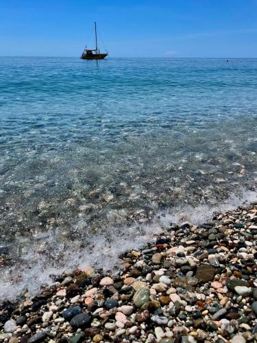 a boat in the water on a rocky beach at Il Glicine Apartment in Letojanni