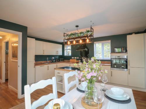 a kitchen with a table with chairs and flowers on it at The Active Recovery Retreat in Stone