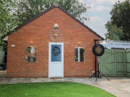 a red brick building with a white door and a clock at The Active Recovery Retreat in Stone