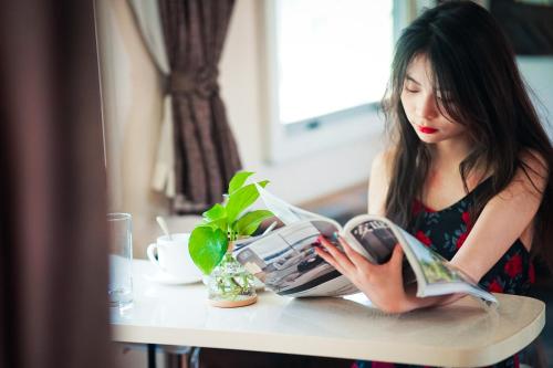 a woman sitting at a table reading a book at Shanyin Xijiang Rustic Luxury Resort Hotel in Bailian