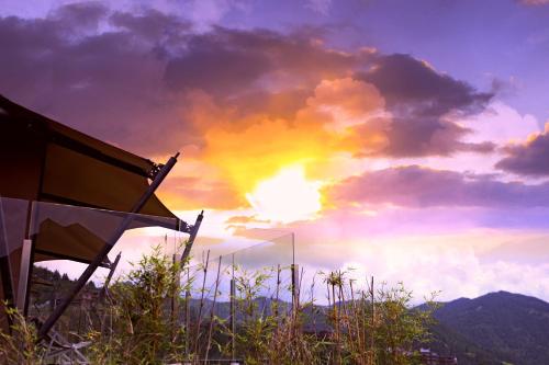 a sunset with a rainbow in the sky at Shanyin Xijiang Rustic Luxury Resort Hotel in Bailian