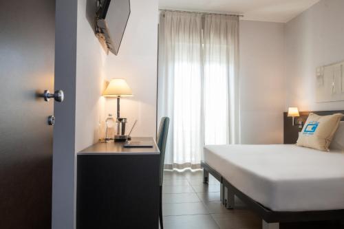 a bedroom with a bed and a desk and a window at The One Hotel - Designed for Adults - Pet lovers in Riccione