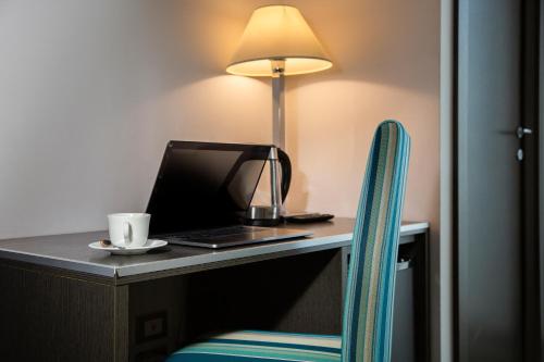 a desk with a laptop and a lamp on it at The One Hotel - Designed for Adults - Pet lovers in Riccione