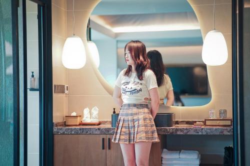 a woman standing in front of a bathroom mirror at Shanyin Xijiang Rustic Luxury Resort Hotel in Bailian