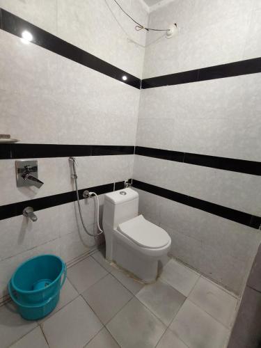 a bathroom with a toilet and a blue bucket at The Ghat House in Varanasi
