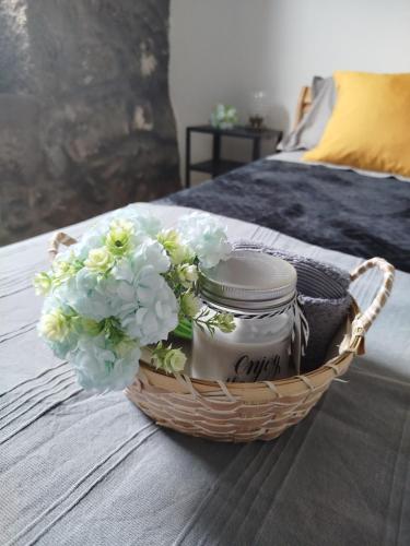 a basket with flowers in it on a bed at Bragada Stonehouse in São Roque do Pico