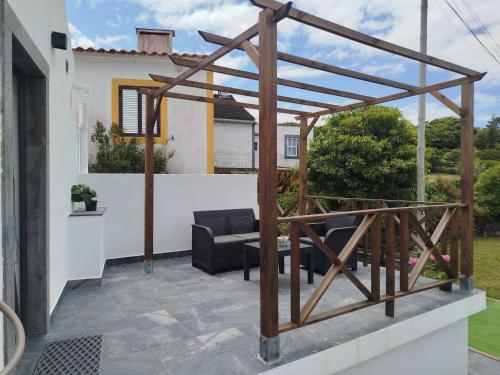 a patio with a wooden pergola and a chair at Bragada Stonehouse in São Roque do Pico