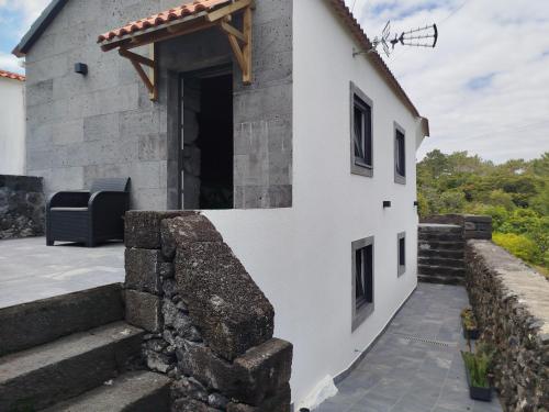 a white house with a stone wall and stairs at Bragada Stonehouse in São Roque do Pico