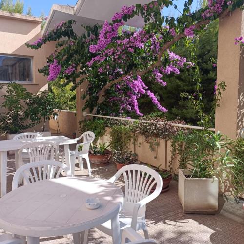 a patio with white tables and chairs and purple flowers at Hotel La Terrazza in Porto San Giorgio