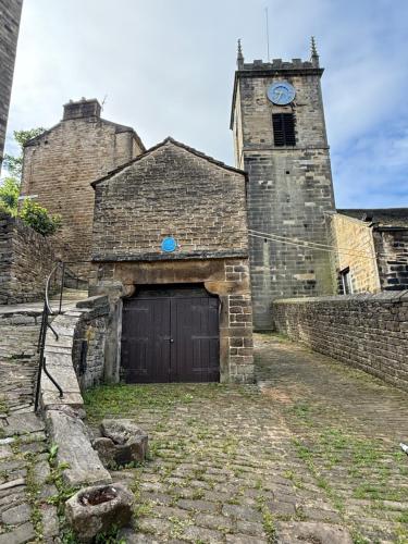 an old brick building with a garage with a clock tower at No.18 Holmfirth in Holmfirth