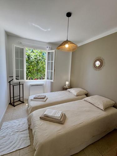 two beds in a room with a window at La Douce Parenthèse in Talence