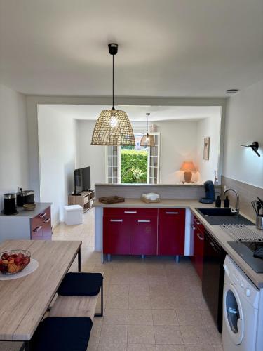 a kitchen with red cabinets and a table and a sink at La Douce Parenthèse in Talence