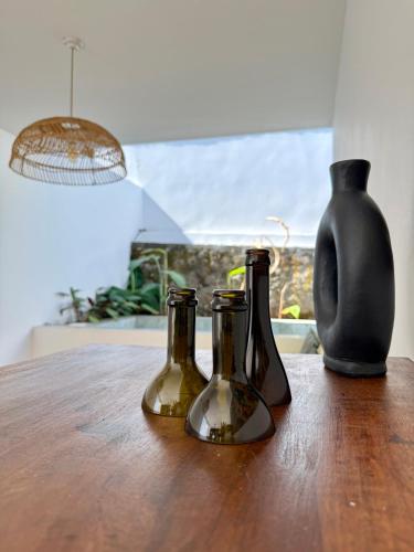 three bottles sitting on a wooden table with a vase at La Kaz Banian in Saint-Pierre