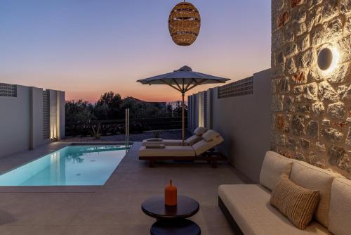a villa with a swimming pool with a couch and an umbrella at Castor & Pollux in Kotrónion