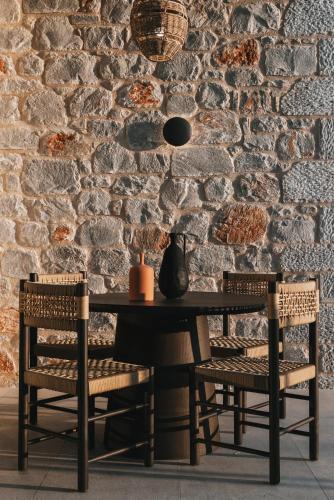 a table and two chairs in front of a stone wall at Castor & Pollux in Kotrónion