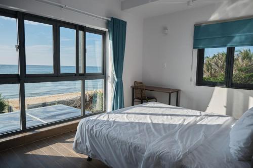 a bedroom with a bed and a view of the ocean at Sea Sand Garden Villa in Phan Thiet