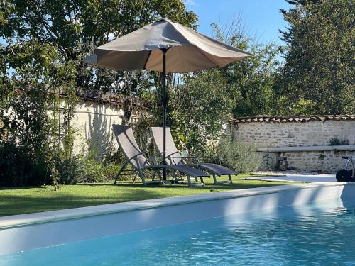 two chairs and an umbrella next to a swimming pool at La Maison de Maître Chagnon Aumagne in Aumagne
