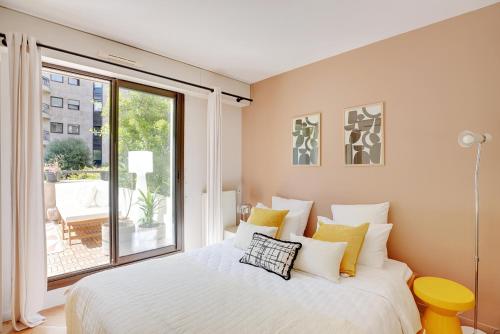 une chambre avec un lit et une grande fenêtre dans l'établissement Appartement proche hôpital américain, à Levallois-Perret
