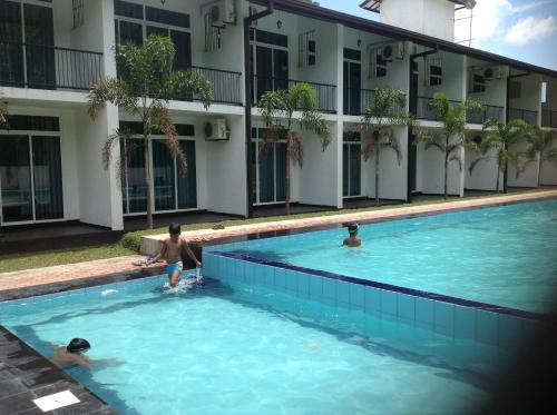 três pessoas numa piscina em frente a um edifício em Samwill Holiday Resort em Kataragama