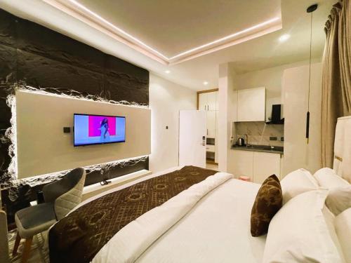 une chambre avec un grand lit et une télévision au mur dans l'établissement Emirates Residence, à Abuja