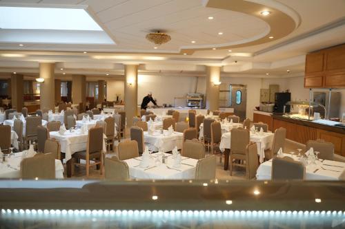 a banquet hall with white tables and chairs and a man at Golf Residence- Families and Couples Only in Hammam Sousse