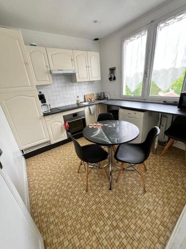 une cuisine avec des armoires blanches et une table et des chaises dans l'établissement Pavillons 6 personnes 15 minutes Disney, à Lagny-sur-Marne