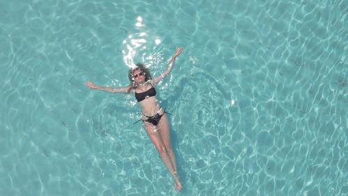 a woman swimming in a pool of water at Madi Maldives Ukulhas in Ukulhas