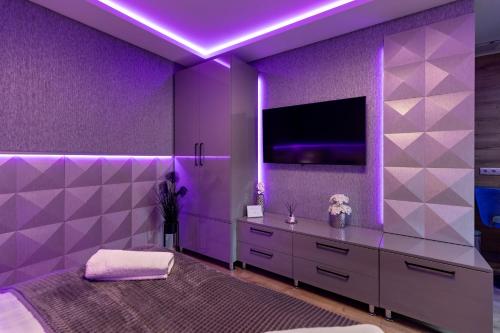 a purple bedroom with a bed and a tv at Royal Apartments Hotel Kecskemét in Kecskemét