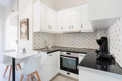 a kitchen with white cabinets and a sink and a table at Seaview Tranquility - Elegant Escapes by the Shore in Ayía Kiriakí