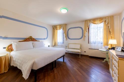 a bedroom with a large bed and two windows at Hotel Colombina in Venice
