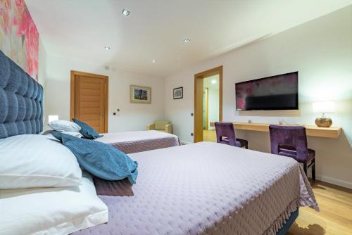 a bedroom with two beds and a desk and a television at Dazzling Lozica Villa 5 Bedrooms Villa Pasija Steam Room & Private Plateau Beach in Dubrovnik